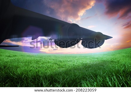 Composite image of airplane cast shadow against green field under orange sky