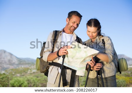 Hiking couple consulting the map in the countryside on a sunny day