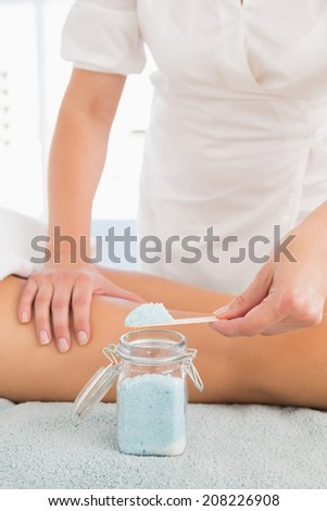 Close up of a beauty therapist using salt scrub at spa center