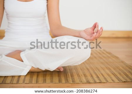 Woman sitting in lotus pose in a white room