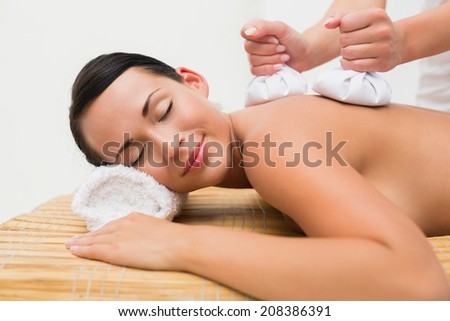 Beautiful brunette enjoying a herbal compress massage in the health spa