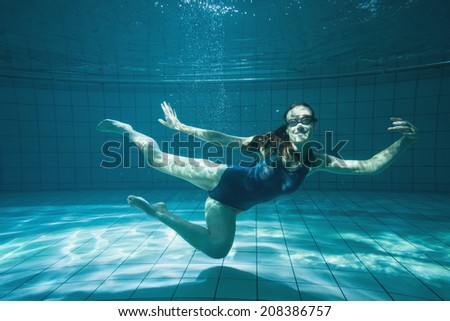 Athletic swimmer smiling at camera underwater in the swimming pool at the leisure centre