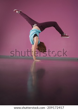 Pretty break dancer doing handstand in the dance studio