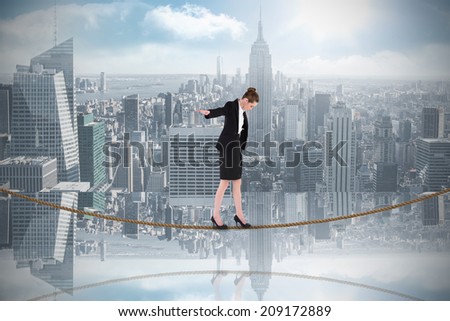 Businesswoman performing a balancing act on tightrope against room with large window looking on city