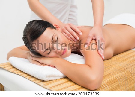 Beautiful brunette enjoying a shoulder massage in the health spa