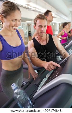 Trainer talking to his client on the treadmill at the gym