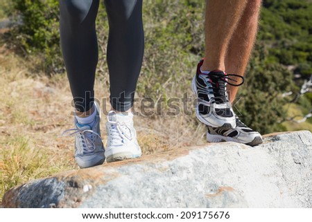 Fit couple jogging up mountain trail on a sunny day