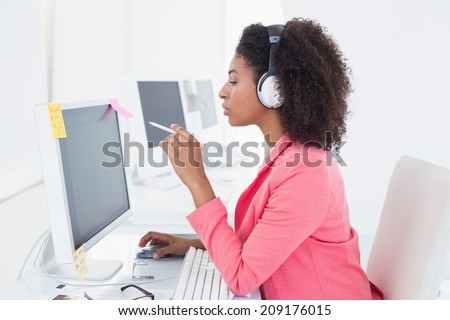 Casual photo editor working at desk listening to music in her office