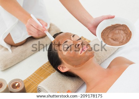 Peaceful brunette getting a mud treatment facial in the health spa