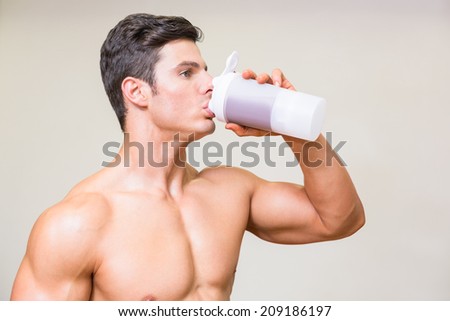 Close-up of a sporty young man drinking protein over white background