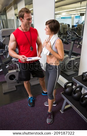 Handsome personal trainer speaking with his client at the gym