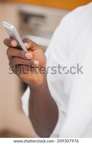 Man in bathrobe holding smartphone at home in the kitchen