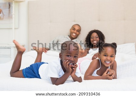 Happy family smiling at camera together on bed at home in the bedroom