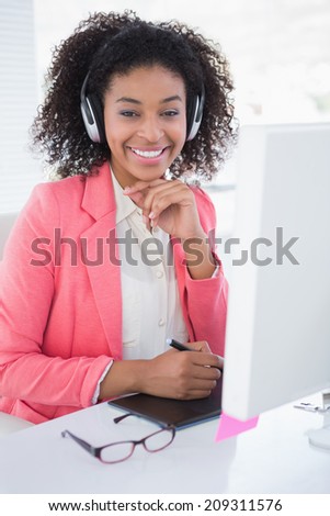 Casual graphic designer working at her desk smiling at camera in her office