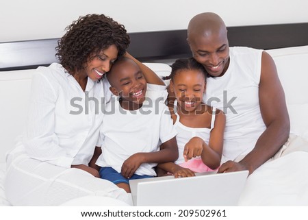 Happy family using laptop together in bed at home in the bedroom
