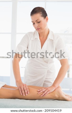 Female masseur massaging woman\'s leg at spa center