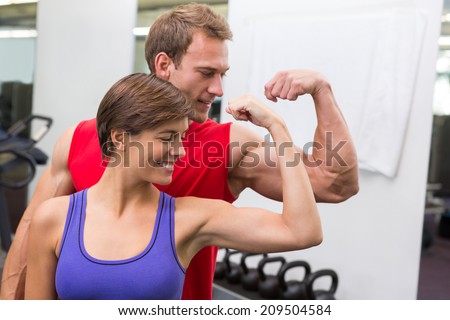 Fit attractive couple flexing their biceps at the gym