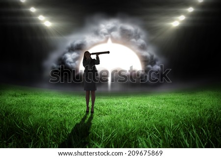 Businesswoman looking through a telescope against football pitch with bright lights