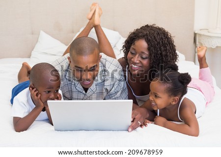 Happy family using laptop together on bed at home in the bedroom