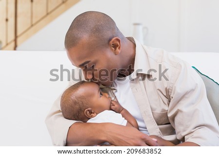 Happy father spending time with baby on the couch at home in the living room