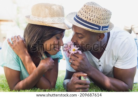 Happy couple lying in garden together smelling flowers on a sunny day