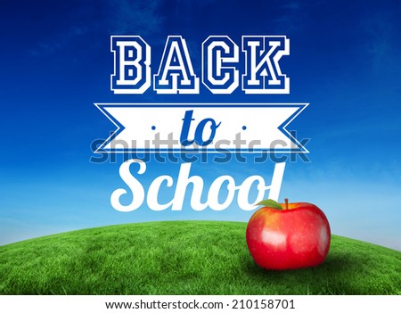 Red apple with back to school message against green hill under blue sky