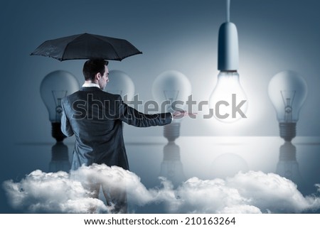 Businessman holding an umbrella with hand out against five light bulbs in a row with one lit up