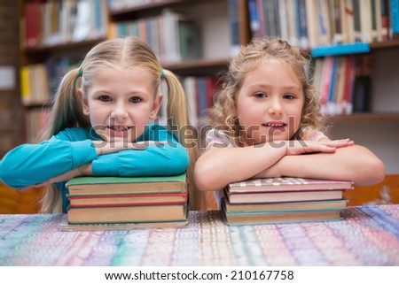 Cute pupils smiling at camera in library at the elementary school