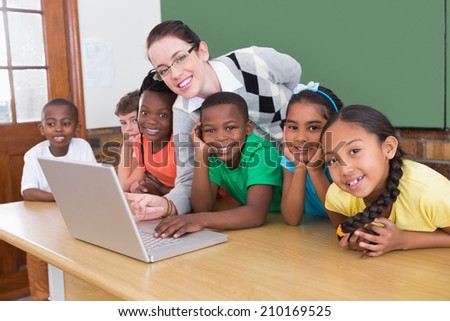 Teacher and pupils working at laptop at the elementary school