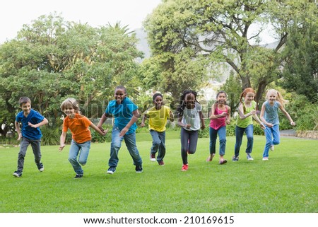 Cute pupils racing on the grass outside at the elementary school