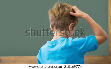 Thinking pupil scratching his head in classroom at the elementary school