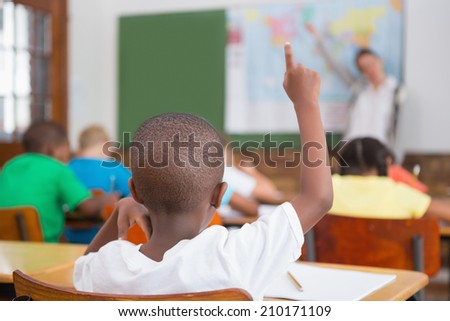 Pupil raising hand in classroom at the elementary school