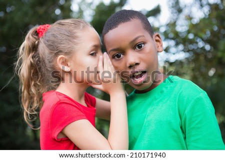 Cute children sharing gossip outside in the park