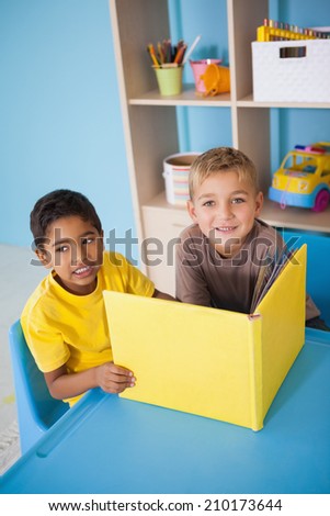 Cute little boys reading at desk in classroom at the nursery school