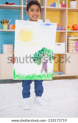 Cute little boy showing his painting in classroom at the nursery school