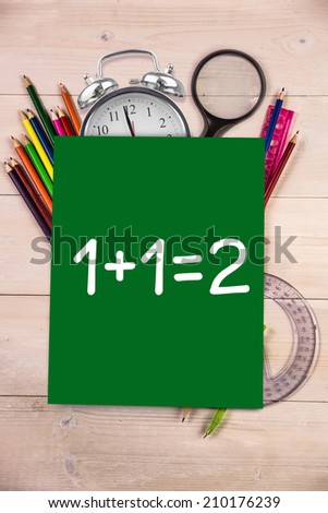 One plus one equals two against students desk with green page