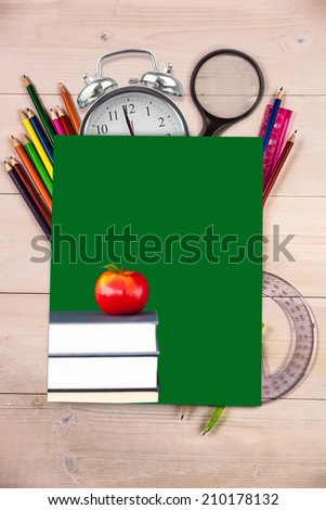 Red apple on pile of books against students desk with green page