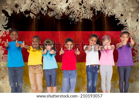 Elementary pupils smiling showing thumbs up against germany flag in grunge effect