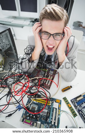 Stressed computer engineer working on broken cables in his office