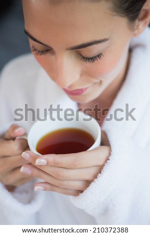 Close up of a beautiful young woman in bathrobe having tea