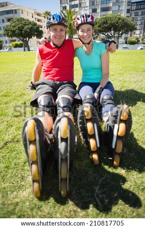 Fit mature couple wearing roller blades on the grass on a sunny day