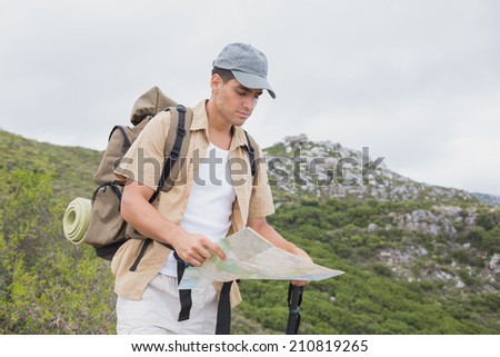 Portrait of a hiking man holding map on mountain terrain