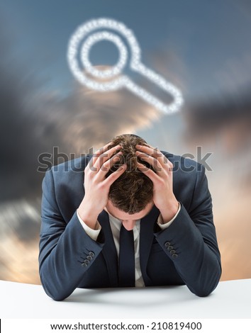 Businessman with head in hands against blue and orange sky with clouds
