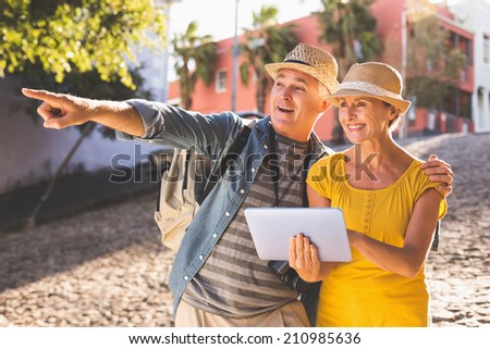 Happy tourist couple using tablet pc in the city on a sunny day