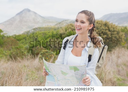 Portrait of a hiking young woman holding map on mountain terrain