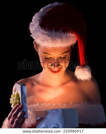Pretty woman in santa outfit opening a gift smiling at it on black background