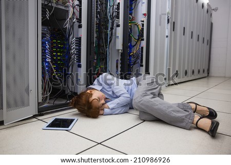 Exhausted technician sleeping on the floor in large data center