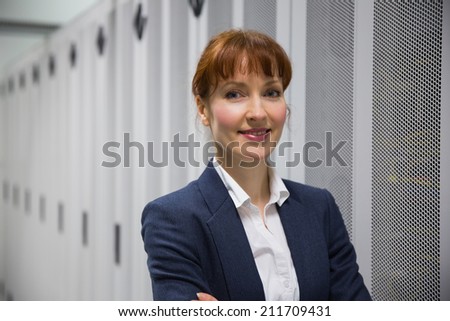 Pretty computer technician looking at camera in large data center
