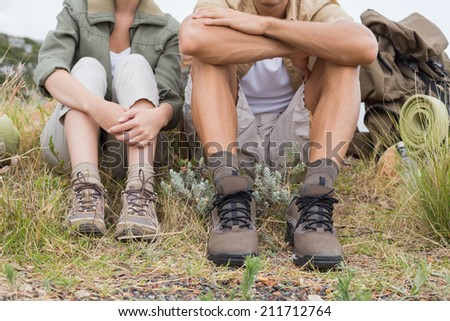 Low section of young couple taking a break after hiking uphill