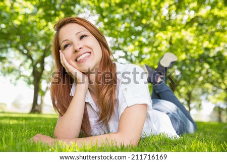 Pretty redhead relaxing in the park on a sunny day